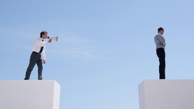 Businessman with megaphone on wall shouting at businessman on wall with gap