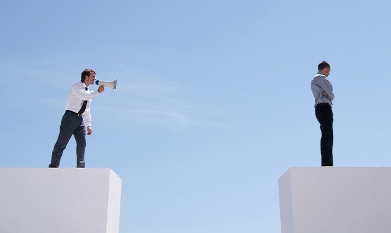 Businessman with megaphone on wall shouting at businessman on wall with gap