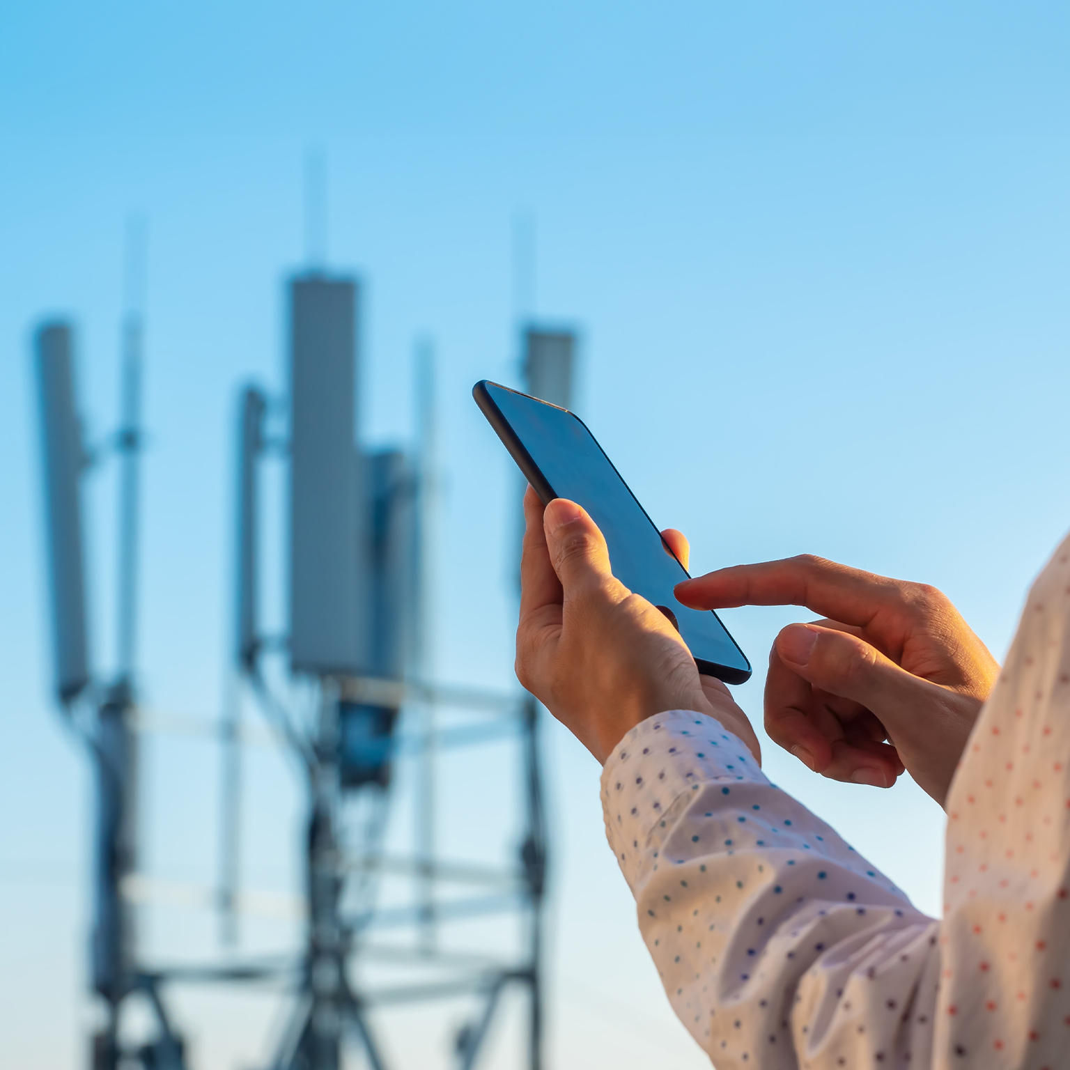 5G communications tower with man using mobile phone - stock photo