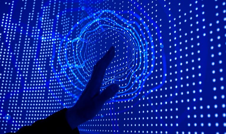 A hand reaching out to touch a deep blue screen covered in datapoint dots. A circular ripple effect emanates from the point of contact.