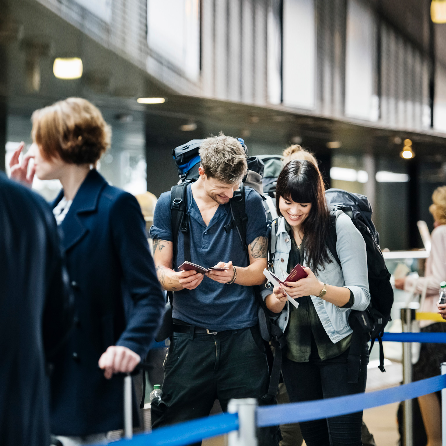 Young backpacker couple waiting at check in counter at the airport - stock photo