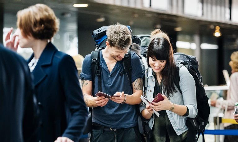 Young backpacker couple waiting at check in counter at the airport - stock photo