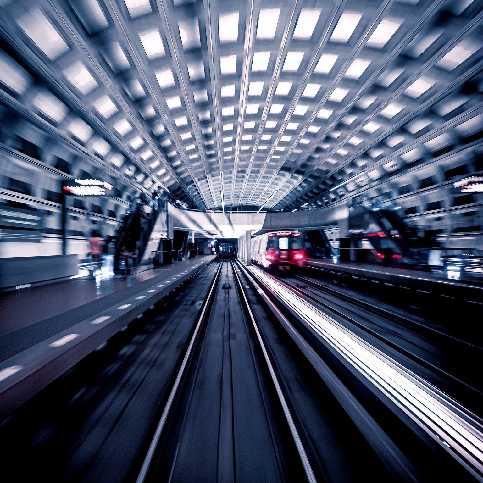 Blurred image of train car leaving the inside of a metro station.
