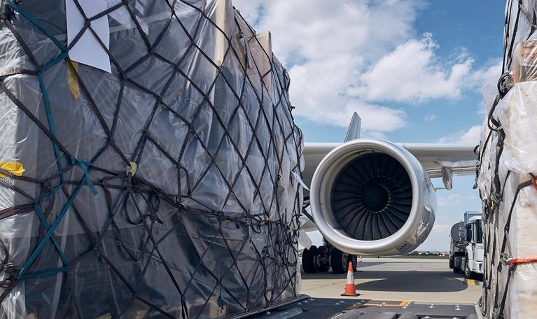 Preparation Before Flight. Loading Of Cargo Containers Against Jet Engine Of Freight Airplane.