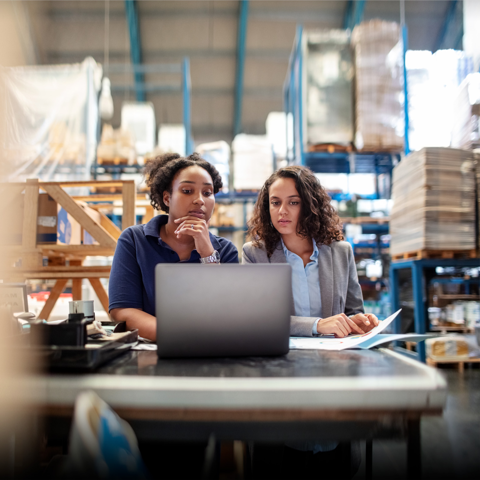 Female factory worker with supervisor working on laptop - stock photo