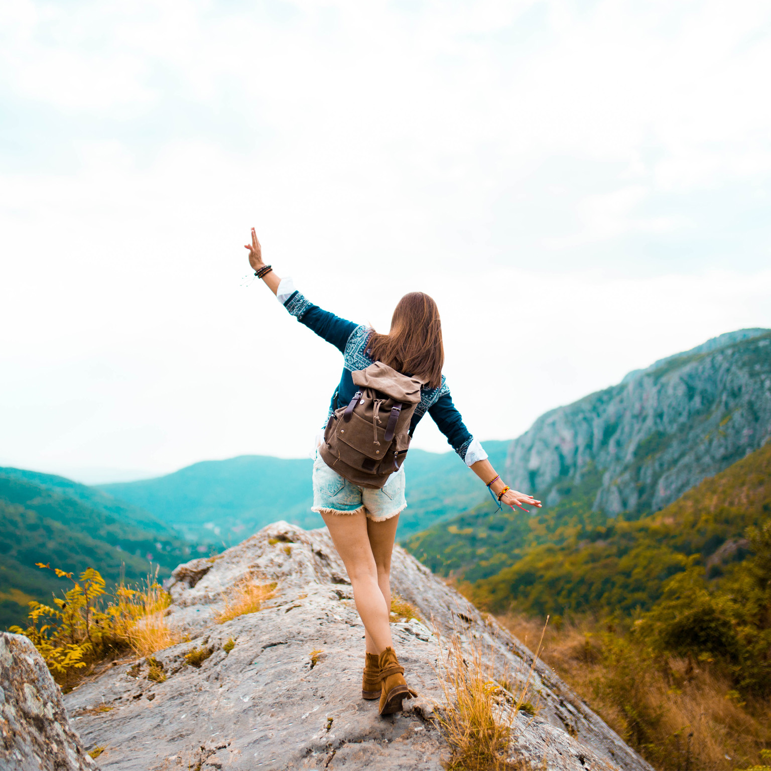 photo girl in hiking boot with backpack walking on rocks