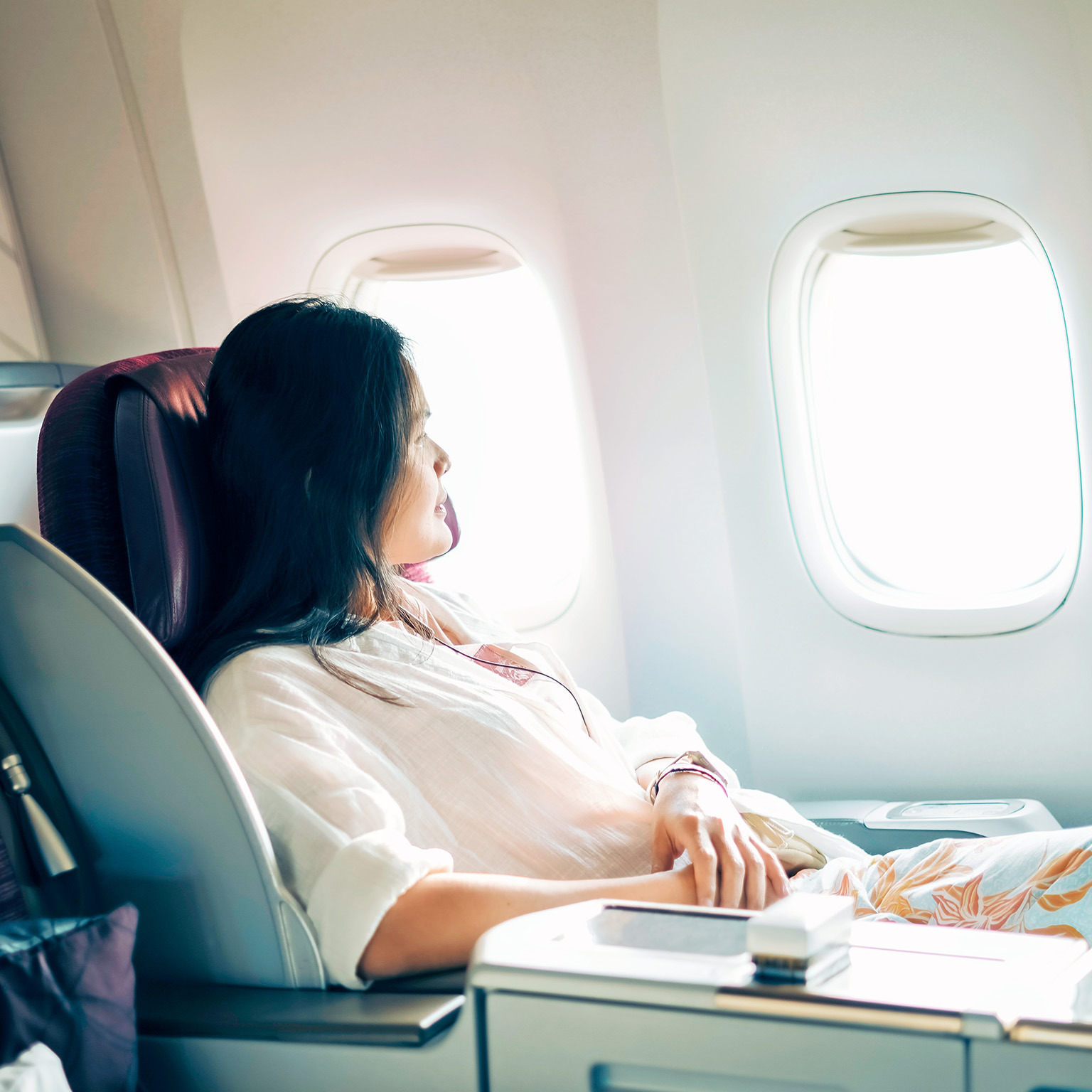A relaxed business class passenger is looking out of the window of a passenger aircraft.
