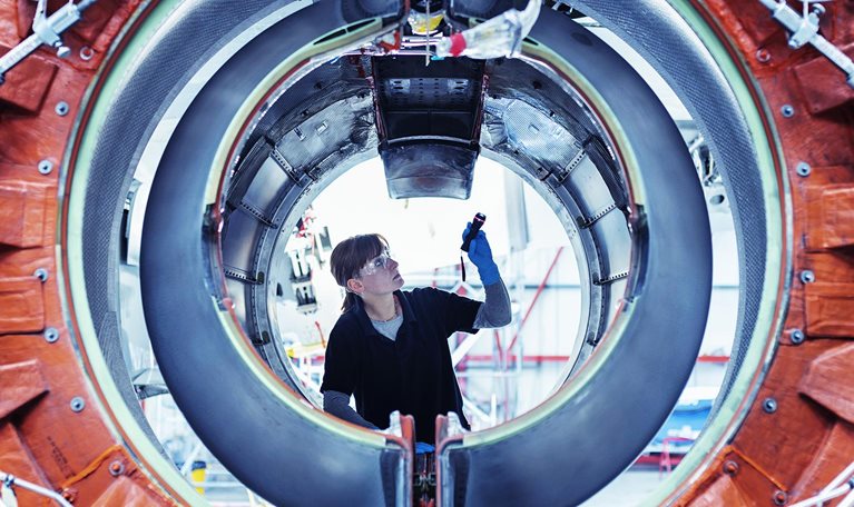 Image of an aircraft maintenance engineer inspecting a jet engine.
