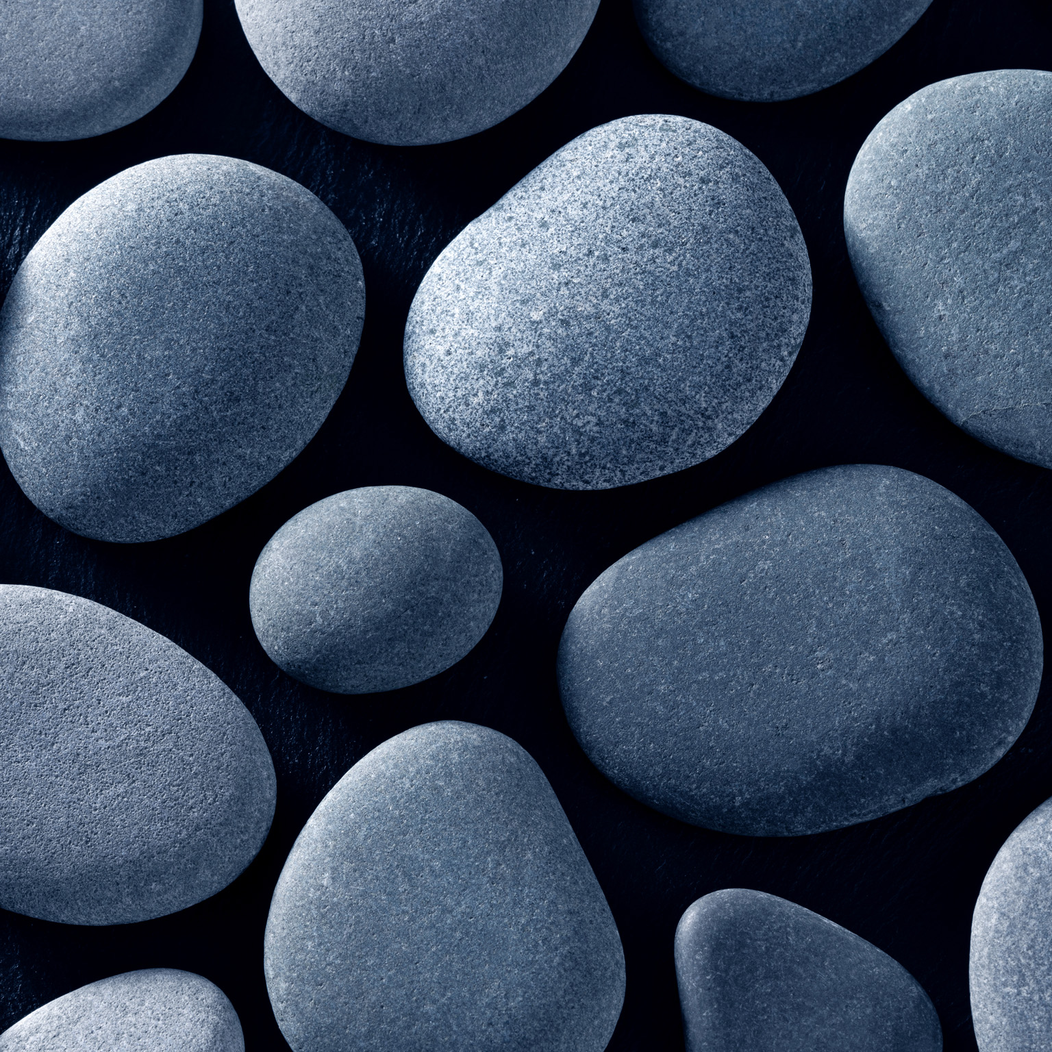 Smooth gray river stones on a black background.