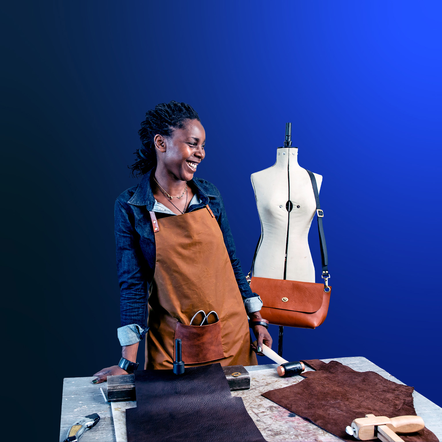 An image of a small business owner sharing a laugh at her design studio, where she makes leather goods to sell in her shop.