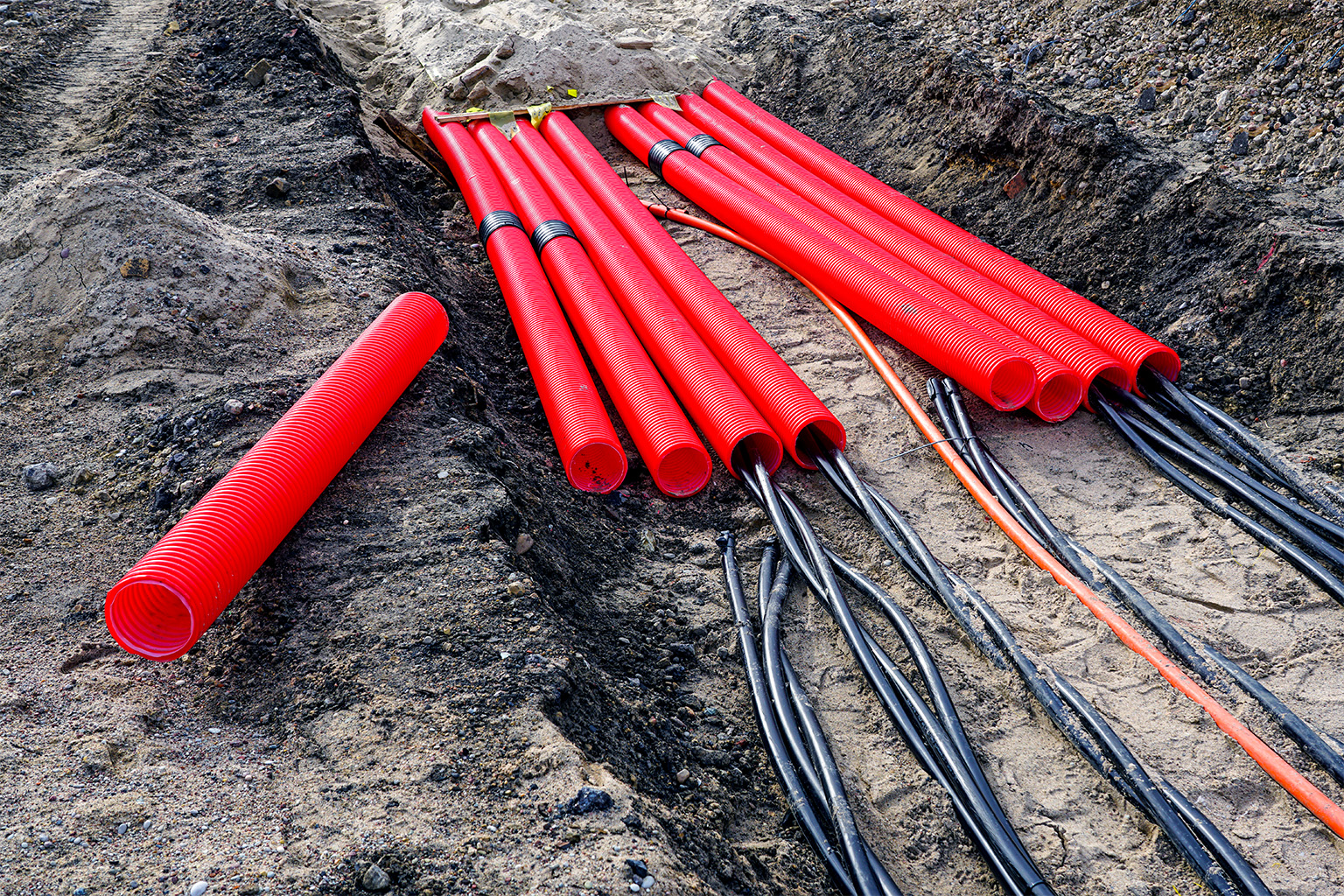 Photograph of powerlines wrapped in red sheathing in a trench.
