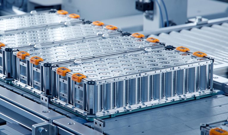 Several large lithium-ion battery modules arranged on an automated production line inside a clean, high-tech manufacturing facility.