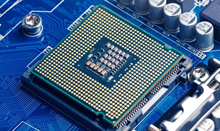 A close-up view of a computer processor mounted on a blue motherboard, surrounded by capacitors, circuits, and electronic components.