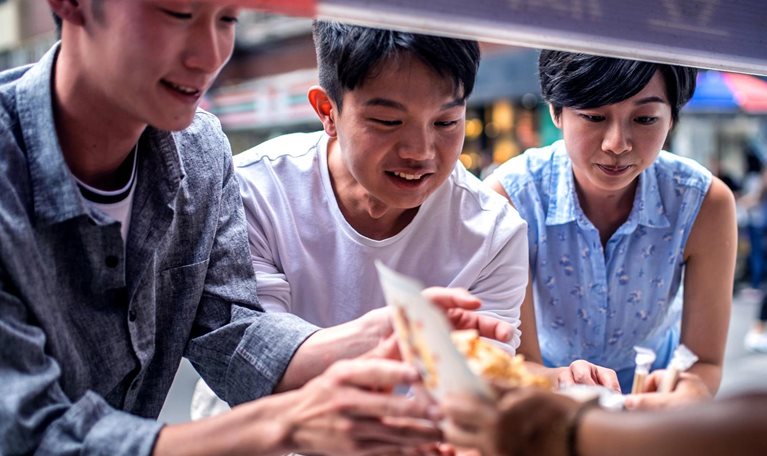 Three people ordering food at a street food counter