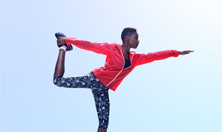 Woman doing yoga in king dancer pose on sidewalk in city
