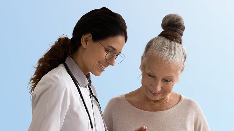 Happy doctor and senior patient use tablet at consultation