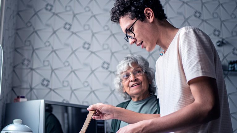 Image of a grandson and grandmother cooking together at home.