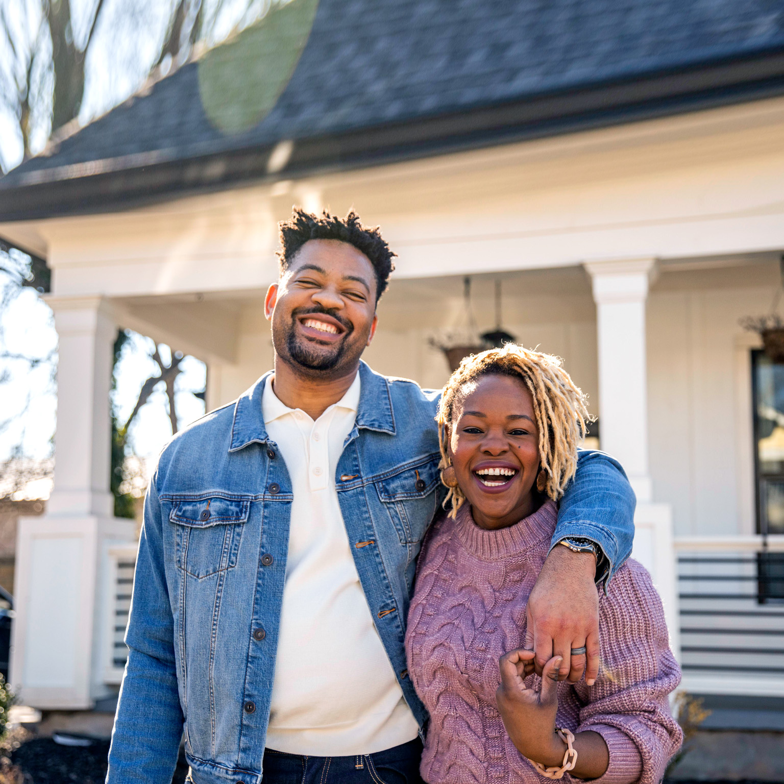 Portrait of husband and wife embracing in front of home