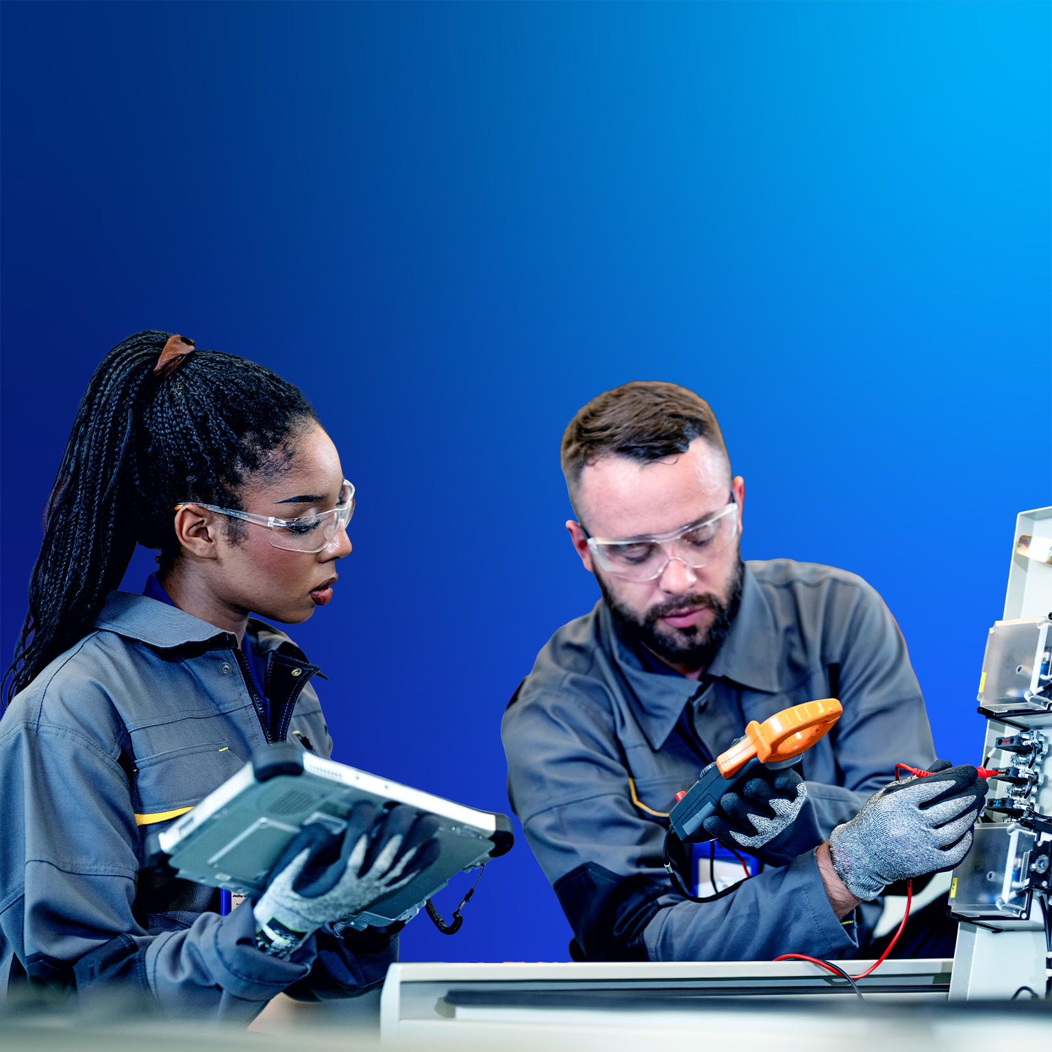 Young man and woman in work coveralls and safety gear have a discussion in a warehouse.