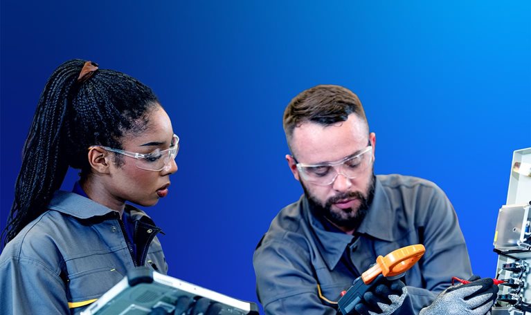 Young man and woman in work coveralls and safety gear have a discussion in a warehouse.
